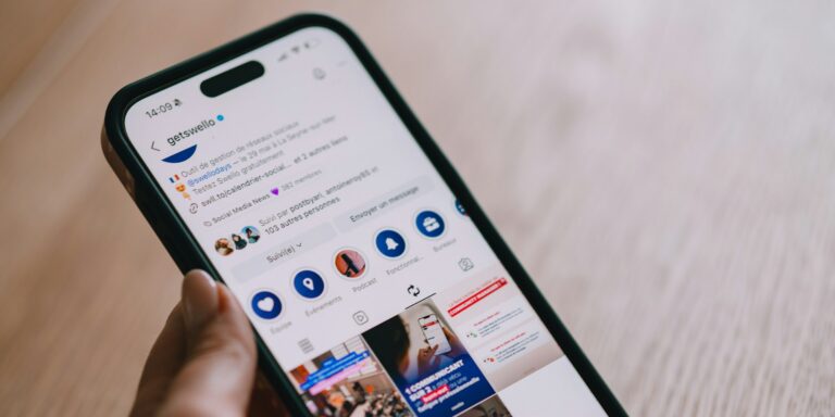 A hand holding a smartphone displaying a social media feed.