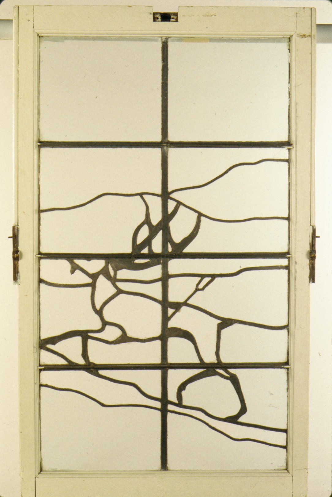 A historical stained-glass window with leaded outlines, clear panes and small colored glass details
