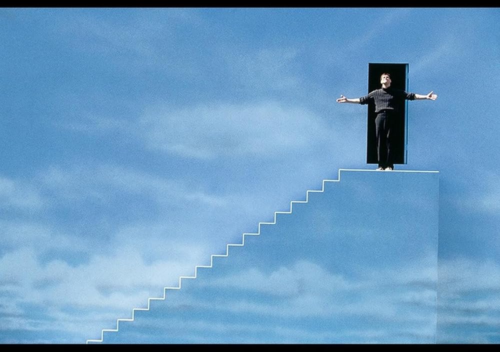 Truman Burbank at the staircase and exit door at the edge of his constructed world in The Truman Show